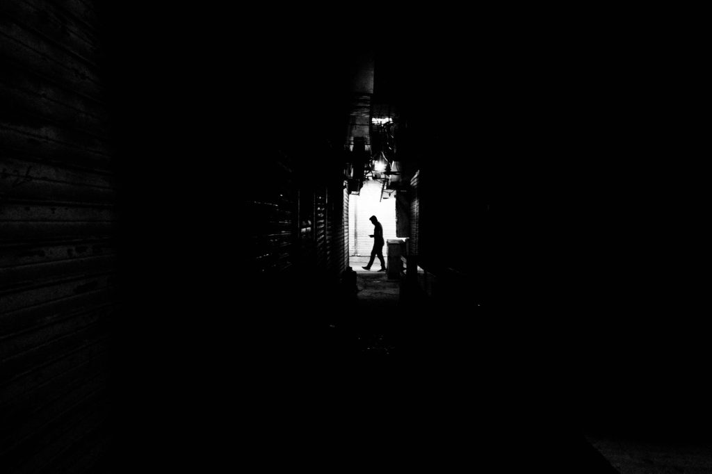 Silhouette solitaire dans une rue sombre évoquant l'assassin Toji Fushiguro