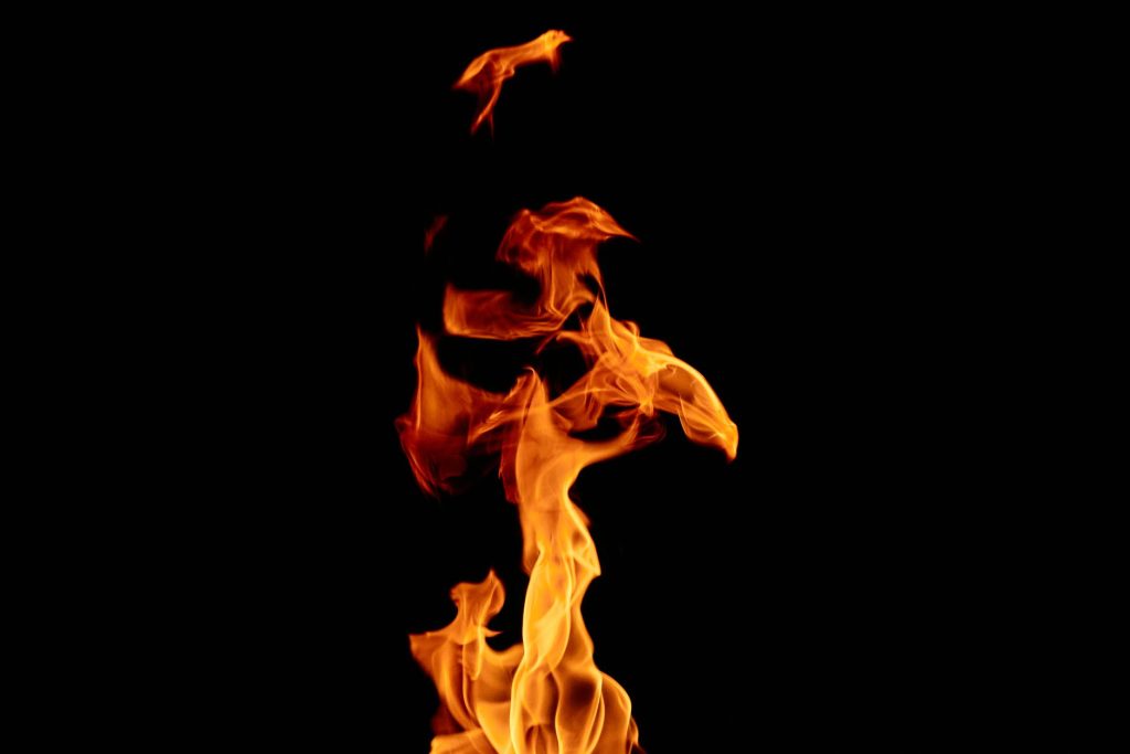 Flammes sombres se détachant sur un fond noir, écho visuel aux flammes d’Amaterasu